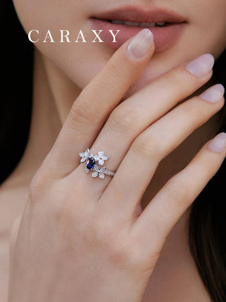 Royal blue sapphire statement ring worn on hand with sparkling floral diamond details.