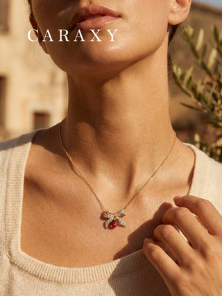 Model wearing a ruby bow pendant necklace with pear lab created ruby and diamond bow design.
