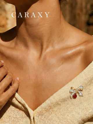Ruby bow pendant worn as a brooch on clothing, featuring pear lab created ruby and diamond accents.