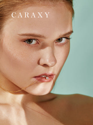 Creative close-up of a model wearing a classic solitaire diamond necklace in yellow gold.