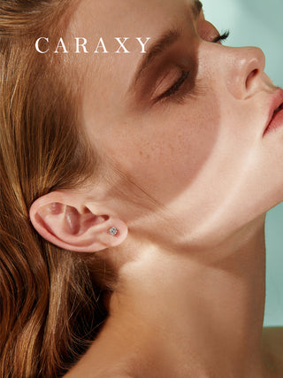 Solitaire diamond stud earrings shown on model with soft natural light.