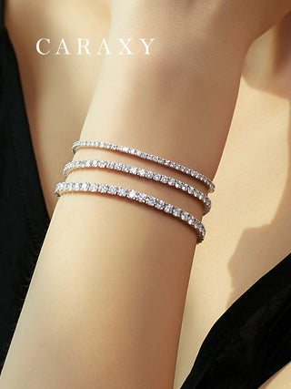 Three lab created diamond tennis bracelets stacked on the wrist in 18K white gold.