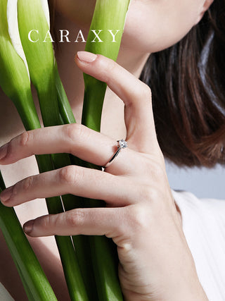 Lifestyle view of a model wearing a cathedral solitaire engagement ring with calla lilies.