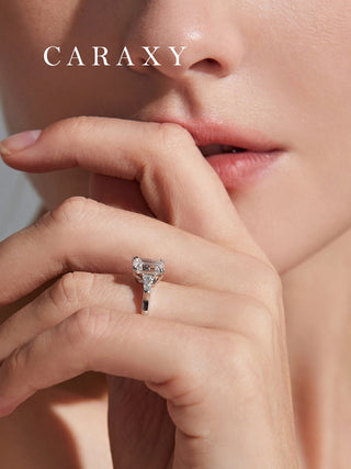 Close-up of emerald cut three-stone ring worn on finger to show scale.
