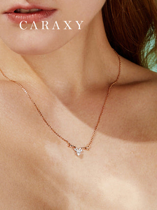 Close view of a model wearing a two-tone necklace with a delicate antler-inspired pendant and a pear-shaped center stone.