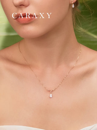 Close-up of a model wearing a pear-shaped lab grown diamond necklace in yellow gold with matching drop earrings from the same collection.